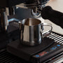 Espresso-Kännchen unter einer Maschine und auf einer Kaffeewaage